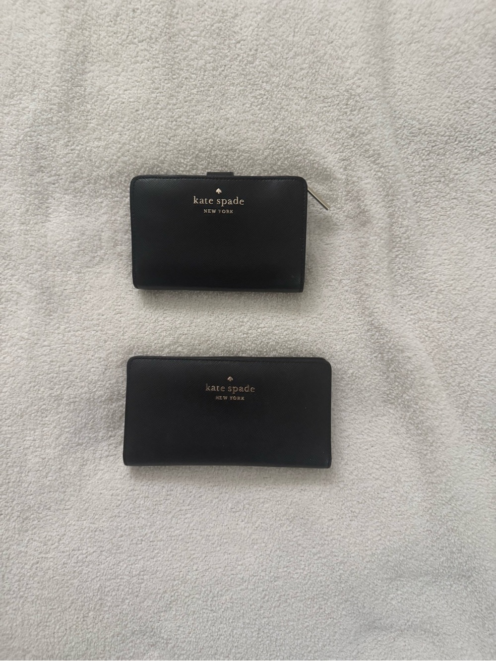 Set of two Kate Spade black leather wallets.